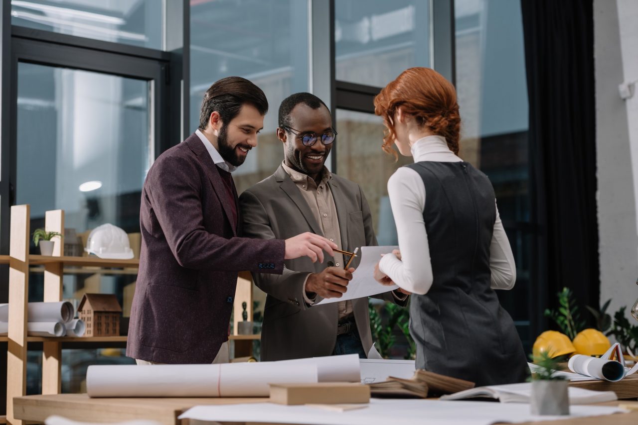 happy-multiethnic-team-of-architects-discussing-documets-at-office.jpg